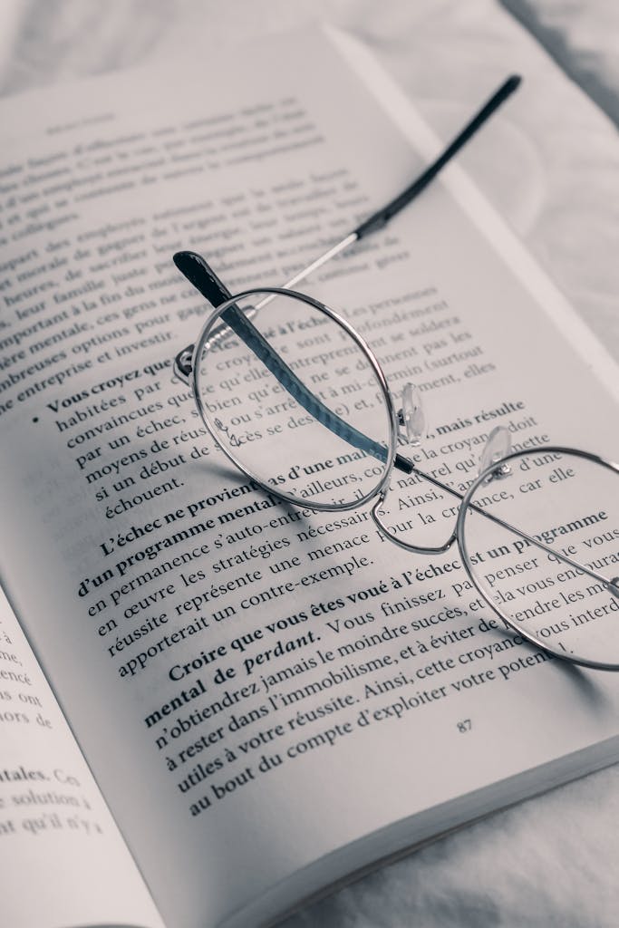 A close-up of eyeglasses on an open book with text in French.